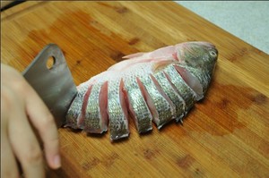 將鱸魚(yú)清洗干凈，從脊椎處切斷至腹部，腹部保留1cm左右不要切斷。