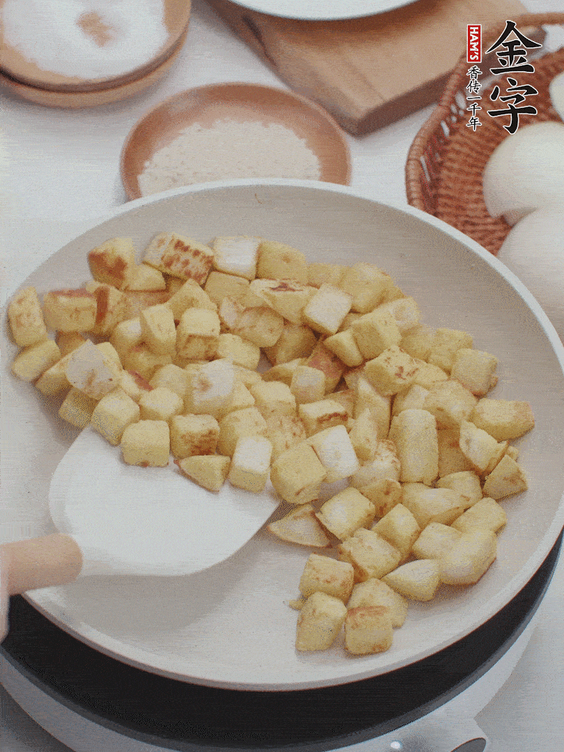 起鍋熱油，倒入饅頭丁，小火煎至蛋液凝固定型再翻面，饅頭丁部煎至金黃時(shí)盛起待用。