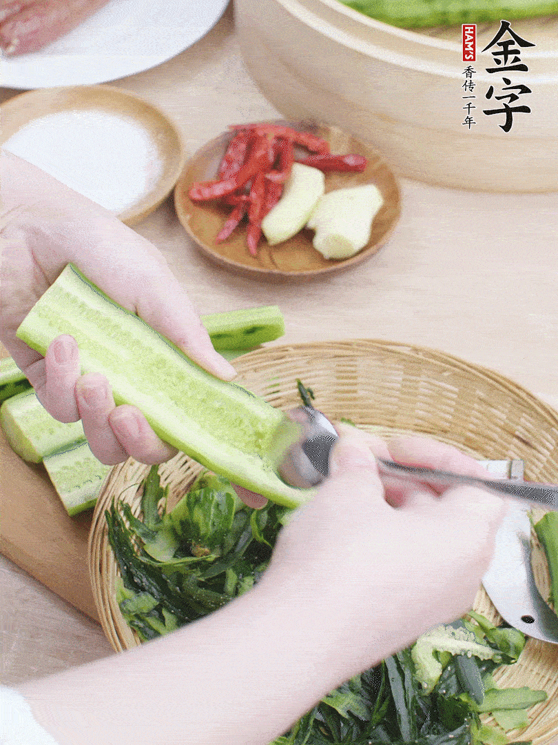 黃瓜削皮，對半切開(kāi)，勺子挖去內瓤，斜刀切片。青蒜斜刀切段。
